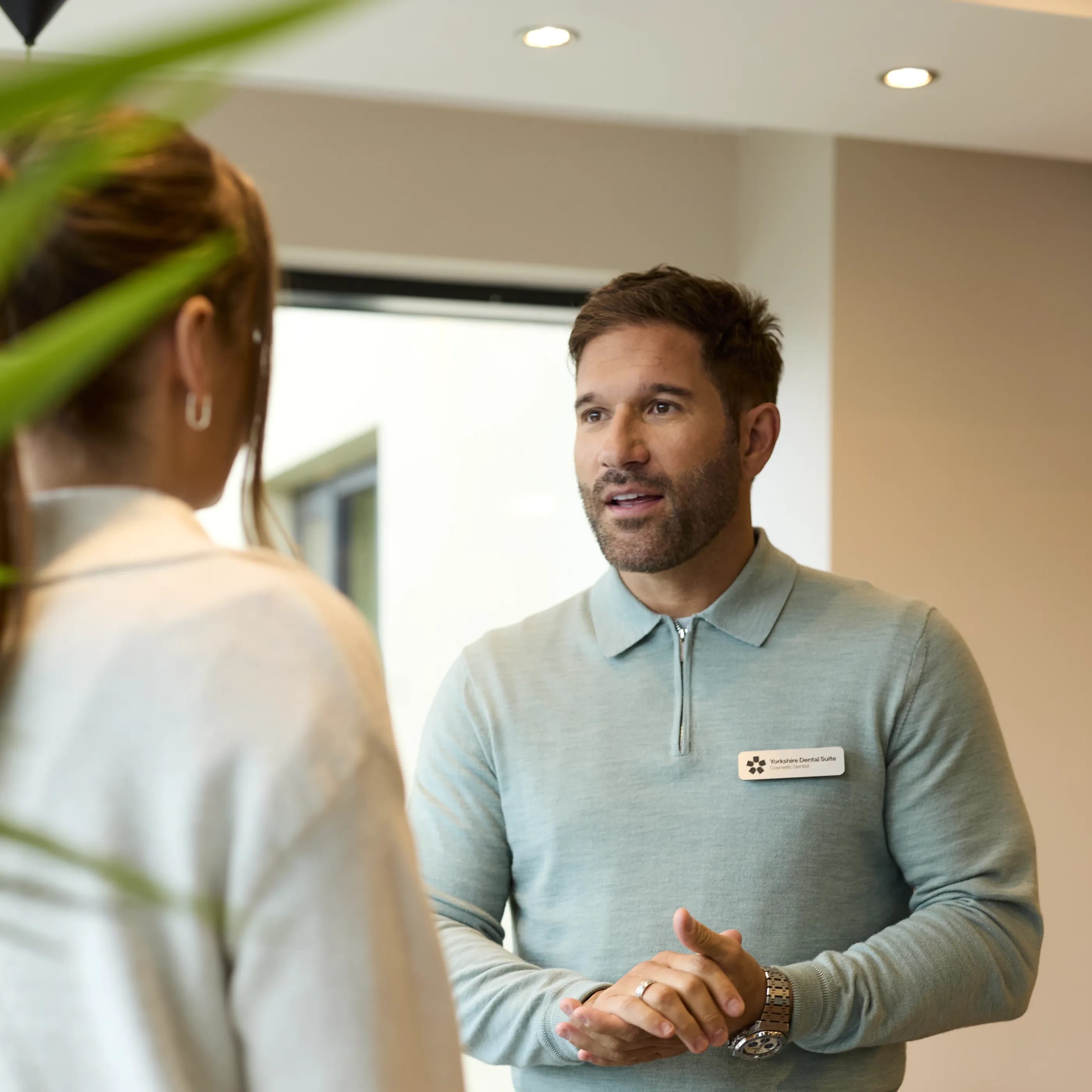 IU porcelain veneers patient waiting in reception (standing, hands clasped)